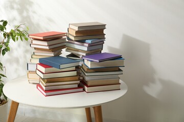 Many stacked books on white table indoors