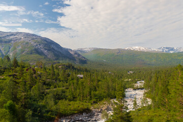 Amazing landscape of the Norwegian country during a perfect summer holiday with wonderful green fields, perfect cloudscape and breath-taking panoramic view as far as you can see with mountains and fjo