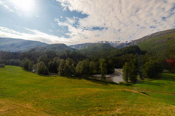 Amazing landscape of the Norwegian country during a perfect summer holiday with wonderful green fields, perfect cloudscape and breath-taking panoramic view as far as you can see with mountains and fjo