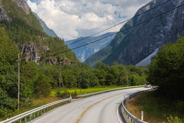 Amazing landscape of the Norwegian country during a perfect summer holiday with wonderful green fields, perfect cloudscape and breath-taking panoramic view as far as you can see with mountains and fjo