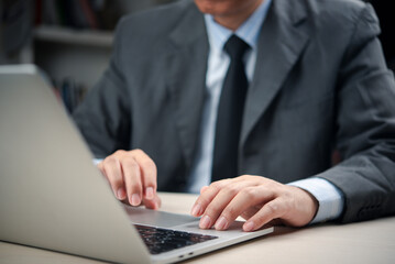 Close-up of male executive hands using laptop touchpad at office desk, professional manager in formal wear analyzing data, sending emails, or managing tasks for business success and productivity.