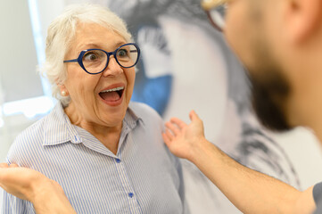 Cropped hands of doctor with excited elderly woman in new eyeglasses screaming after successful surgery