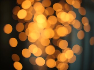 Obraz premium Warm golden bokeh lights softly floating on a dark blurred background, creating an elegant festive glow perfect for holiday branding, seasonal designs, elegant invitations, or luxurious