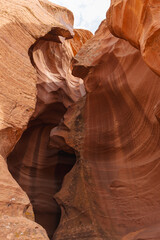 Close-up view of dramatic sandstone canyon walls with swirling textures and smooth curves, showcasing natural erosion patterns and rich earthy tones of red and orange.
