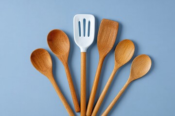 Wooden kitchen utensils arranged on blue background showcase the