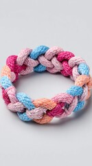 Fototapeta premium Colorful braided bracelet made from soft material seen on a light background showcasing intricate weaving and design