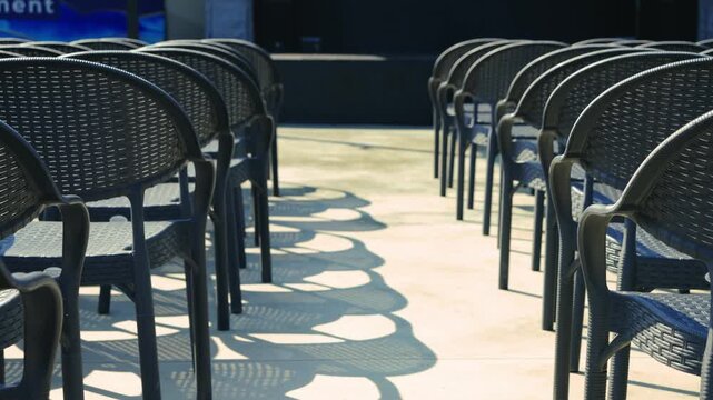 En
Rows of empty chairs stand in front of the stage before the start of a performance or concert.
