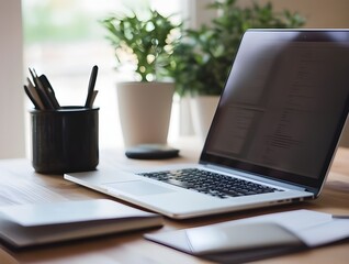 modern laptop computer on clean wooden desk with office supplies in bright workspace