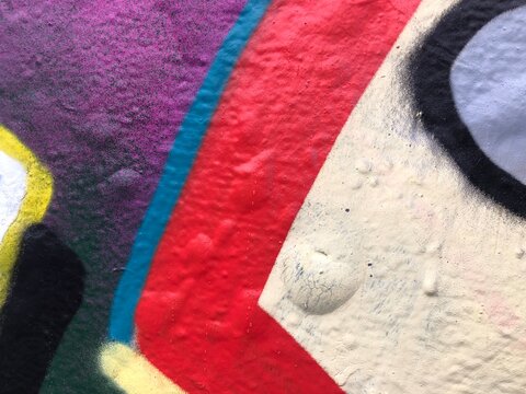Close-up thick textured spray paint urban wall red, blue, white, black, purple, violet graffiti textures