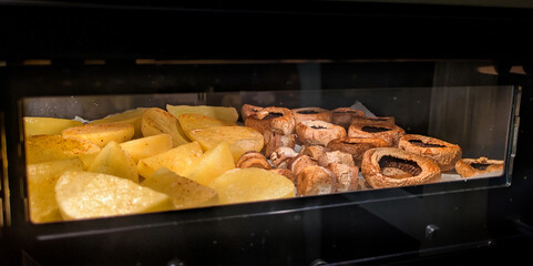 Slices of baked potatoes and mushrooms on a baking sheet in the oven