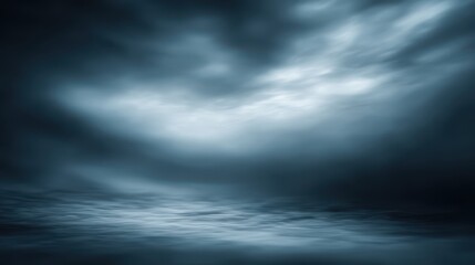 Dark, dramatic sky over rippling water, with ethereal light breaking through stormy clouds. A moody, abstract landscape scene evoking mystery and depth, blurred blue background