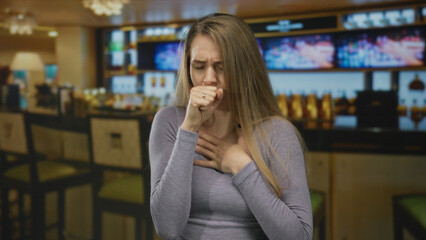 Woman experiencing discomfort while coughing in a busy restaurant setting, surrounded by a bar environment, lcd screens, and ambient lighting, conveying urgency and health concern.