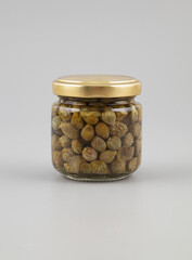 Capers in a glass jar on a white background. Isolated