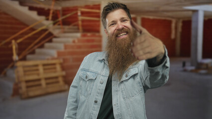 Fototapeta premium Man with denim jacket extends hand gesture toward the camera amid brick walls in an unfinished building; trust.
