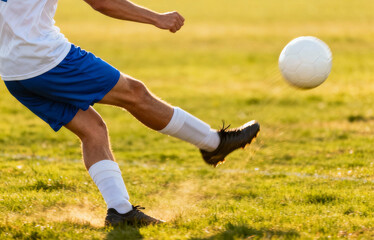 Naklejka premium Soccer player kicks the ball with force outdoors