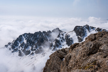 Dramatic high mountain landscape with snow, rocks and low clouds