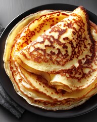 Deliciously cooked crepes served on a black plate with a dark background at a cozy kitchen setting