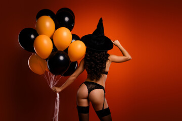 Glamorous witch conjures Halloween magic in stylish outfit with balloons, embodying festive allure...