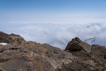 Dramatic high mountain landscape with snow, rocks and low clouds