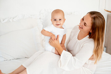 mother and baby hugging and kissing on the bed at home, maternal love and care, mother and child