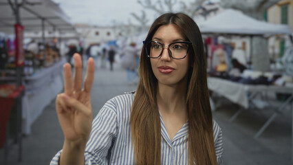 Young hispanic woman wearing glasses raising fists with open mouth smile on street with market...