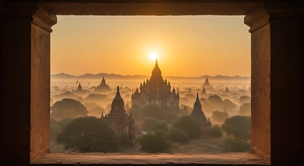 Sunrise over ancient temple structures seen through a window frame at dawn