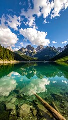 Serene mountain lake reflecting a vibrant sky and clouds, clear shallows with rocks and a fallen log visible in the foreground