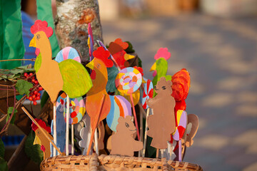Colorful handmade chicken decorations displayed at a crafts market in a sunny outdoor setting