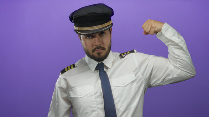 Young man in pilot uniform flexing arm confidently against a vibrant purple background, showcasing...