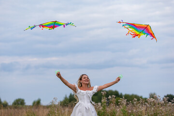 Girl flying colorful kites in an open field during a cloudy day in summer
