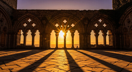 Beautiful sunrise through the arches of the ruins of an ancient abbey with the sun shining through the windows and casting shadows