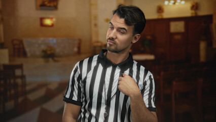 Obraz premium Young hispanic referee man gesturing inside a church setting, suggesting a playful or officiating moment in the serene indoor environment.