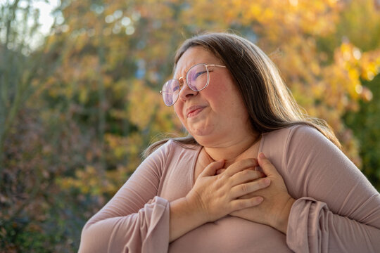 Middle-aged woman experiencing chest pain, pressing hands to heart. Concept of health problems, cardiac arrest, and distress, Health risk, heart failure, and emergency situation