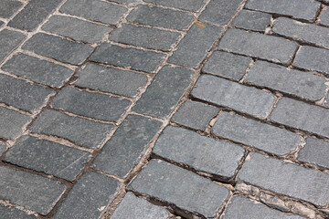 The old street is paved with paving stones. Background of dark stones laid on the road in an ancient city. Paving stones in an ancient city.