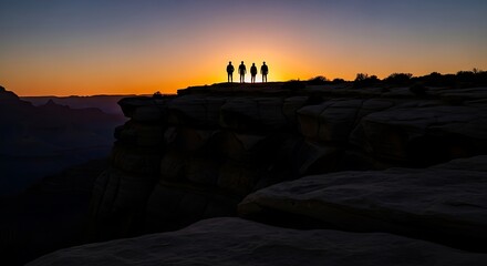 Silhouetted figures stand on a cliff edge at sunset, overlooking a vast landscape.