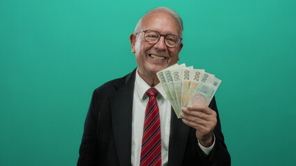 Senior man joyfully holding czech koruna banknotes in front of a green background, illustrating...
