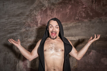 Horror Halloween scene with vampire man with bloody fangs screams in gothic hood