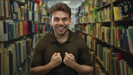 Man points finger to chest amid books on crowded library shelves inside a building aisle; excitement discovery.