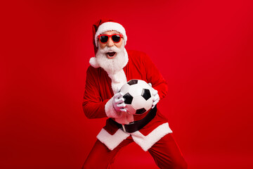 Santa Claus with sunglass holding a soccer ball on a red background embracing holiday fun and sporty vibes