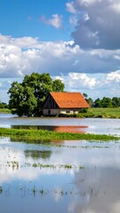 Obraz premium Rustic farmhouse in flooded field under a partly cloudy sky