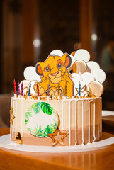 Festive cake with Simba figurine, gold stars, and candles.