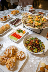 Top view of a lavish table with roasted meat, salads, desserts, and appetizers.