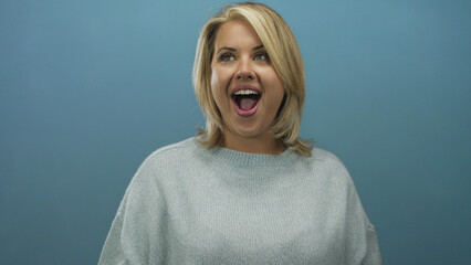 Young blonde woman wearing grey sweater seen in side profile with mouth open in gasp gesture in...