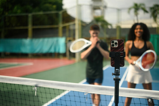 Close-up of a Mobile phone on stand broadcasting a live tennis practice, capturing active players during training