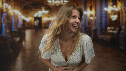 Fototapeta premium Woman laughing with hands covering mouth, polka dot dress and windblown hair in ornate museum building; spontaneity joy playfulness warmth.
