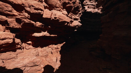 Warm hues reflect off towering rock formations as evening approaches in a secluded canyon. Shadows deepen, creating a sense of mystery and adventure in natural surroundings.