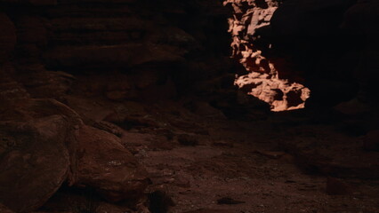 Golden sunlight pours into a dark cave, highlighting the rugged rocks and earthy tones. Shadows dance as the last light of day creates a mysterious and enchanting atmosphere.