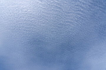 Blue sky with soft altocumulus clouds forming wave-like texture