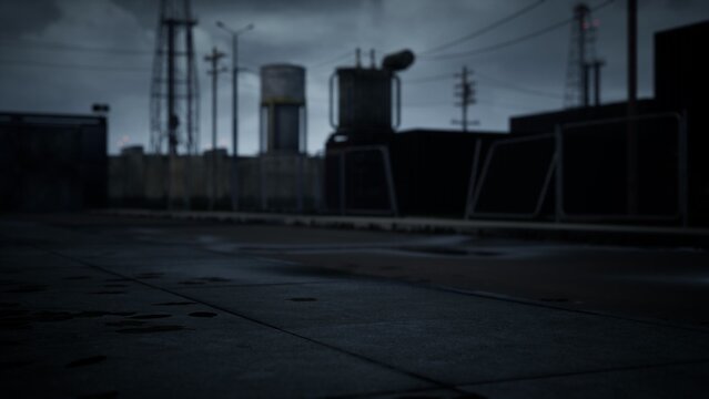 Dim lighting casts shadows over an industrial area, hinting at recent rain. Dark structures loom while power lines create a stark silhouette against stormy clouds, evoking an eerie atmosphere.