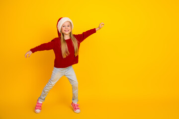 Funny little dancer in red sweater santa hat leaps joyfully across bright yellow background creating merry holiday vibe for kids fun campaign